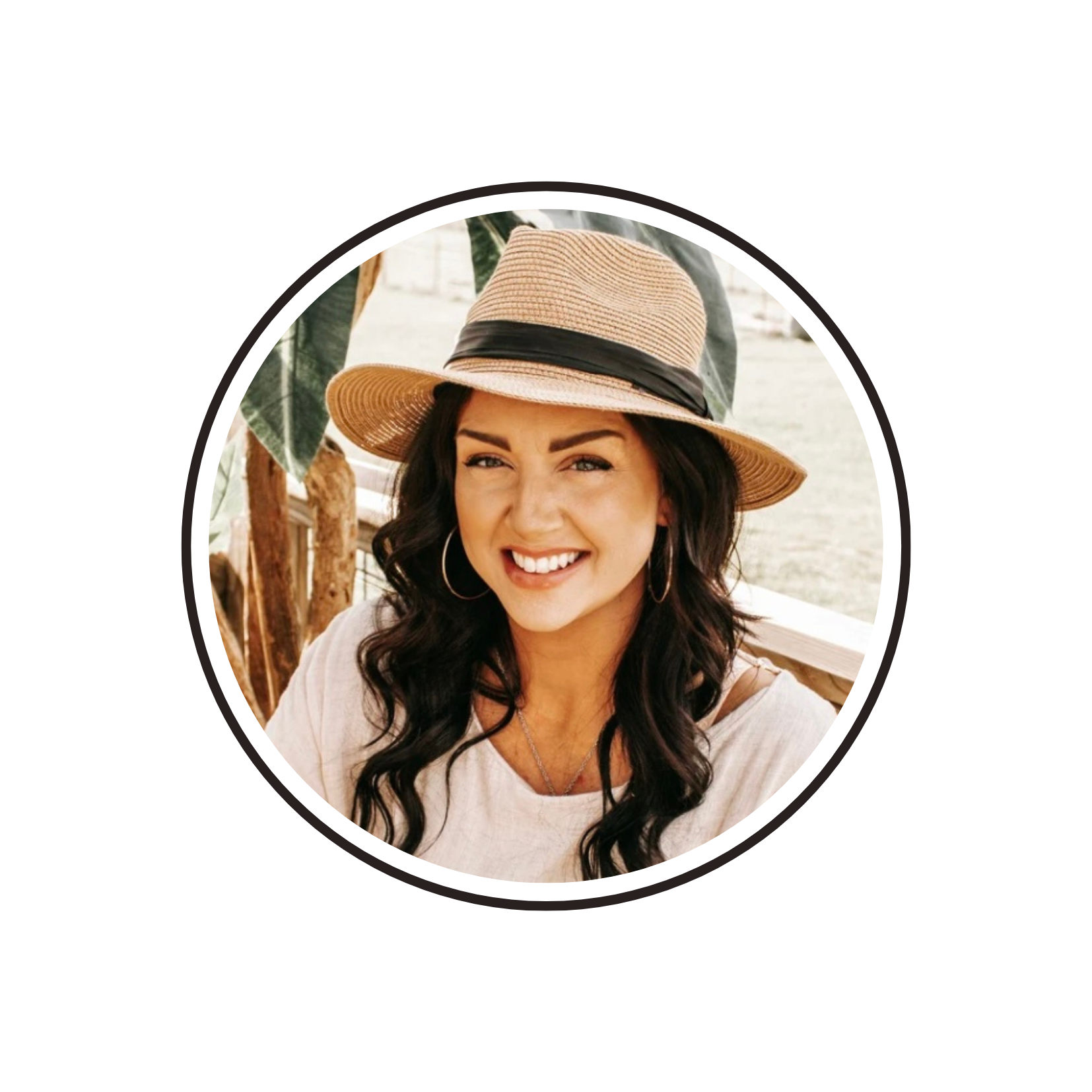 Woman wearing a hat while sitting at a table outside.