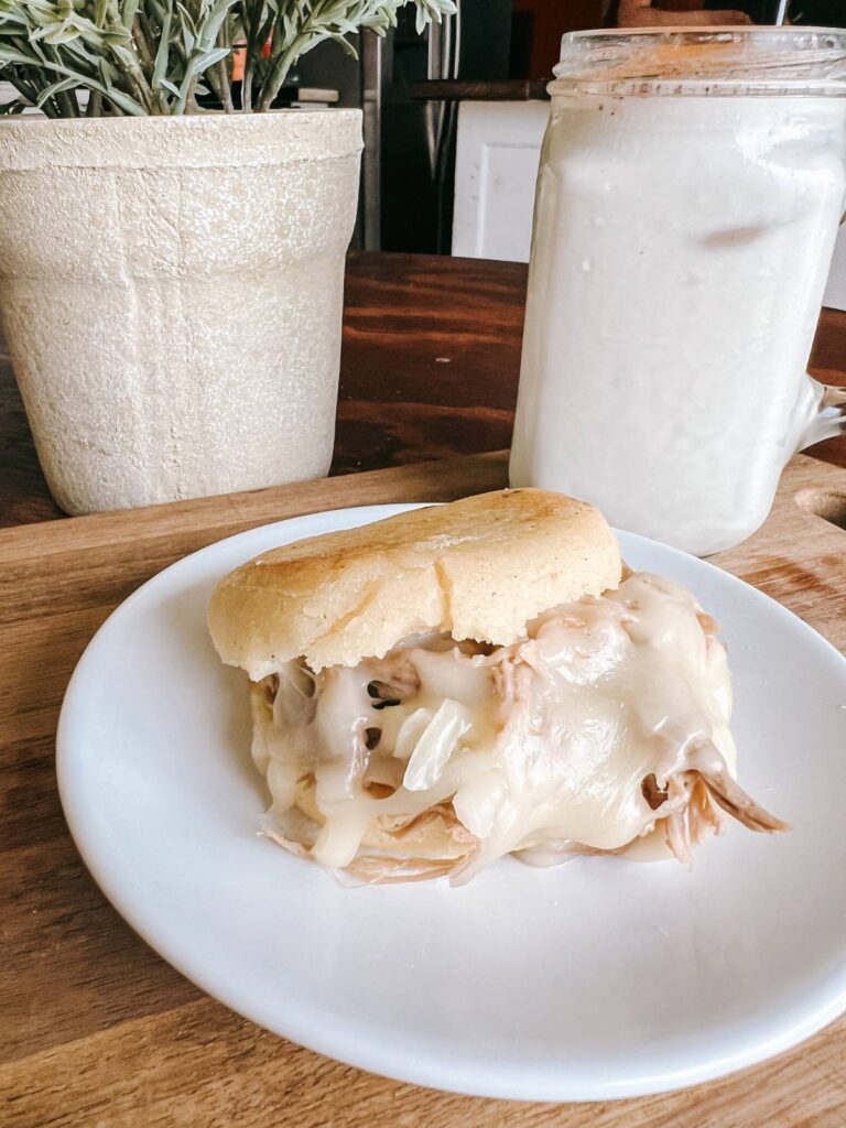 arepa sandwich and chicha drink on table.
