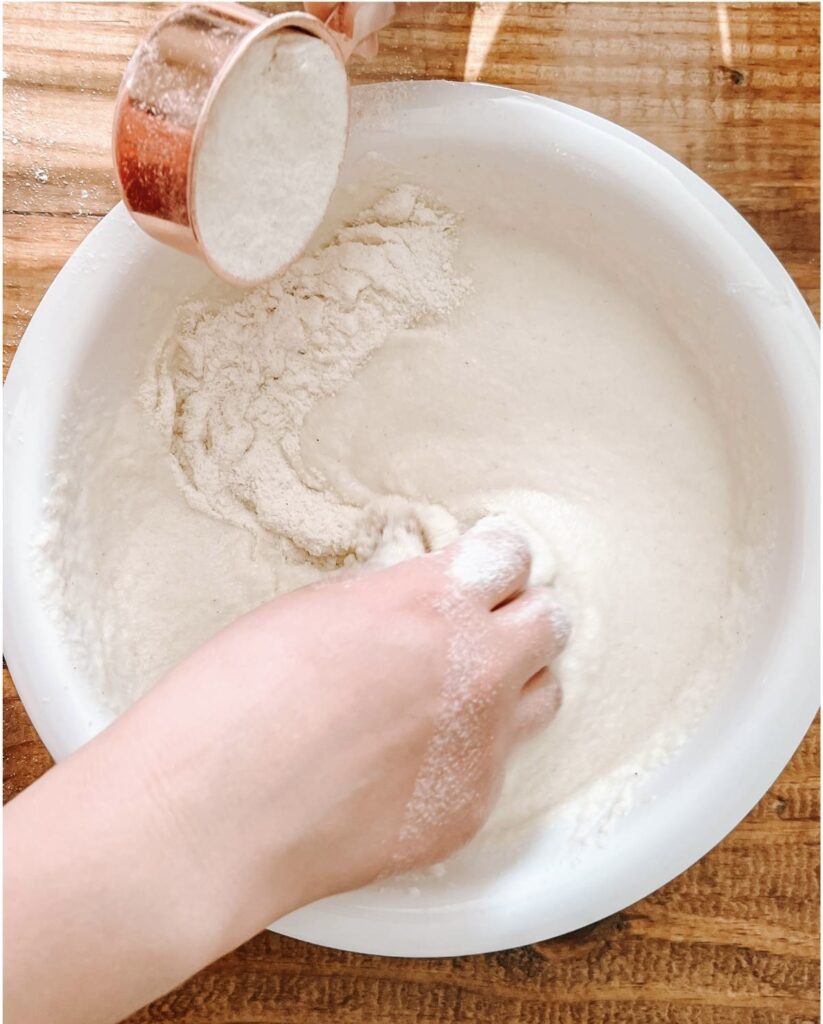 white bowl with arepa flour and water being mixed together.