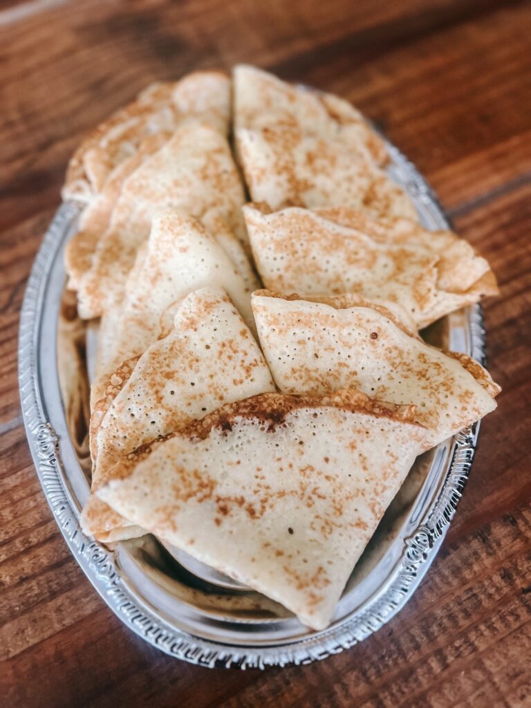 Folded crepes neatly placed onto a silver serving tray.